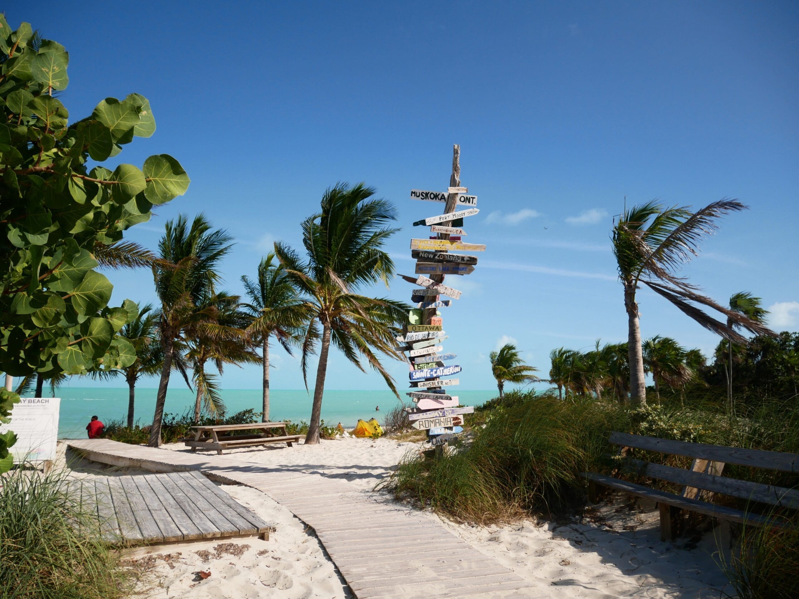 Destination signpost with world locations on a sandy beach path in Providenciales Turks and Caicos